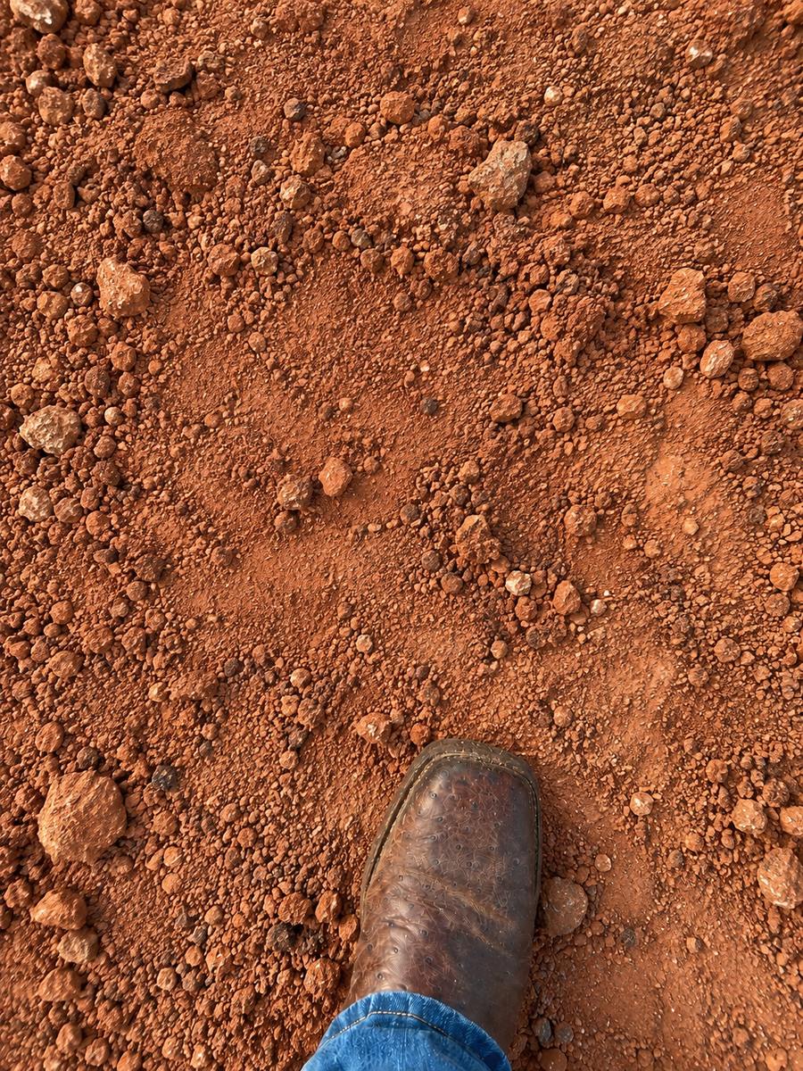 Red select fill dirt with a work boot for scale