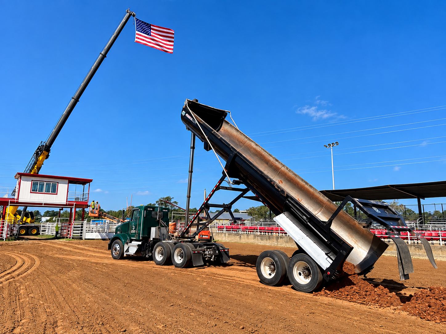 Dump truck with its bed raised, unloading material onto a dirt lot